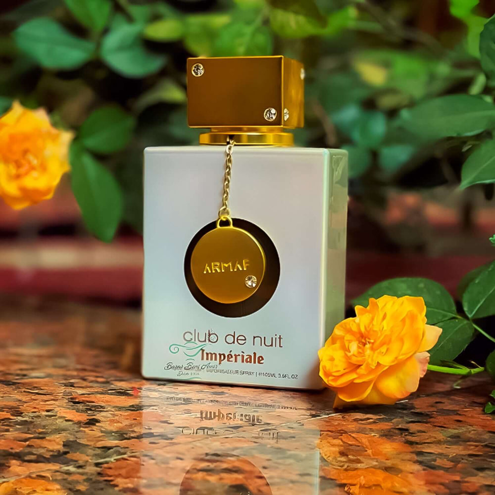 Frasco de perfume Club de Nuit Imperiale de Armaf, 105ml para mujeres, con flores de fondo.