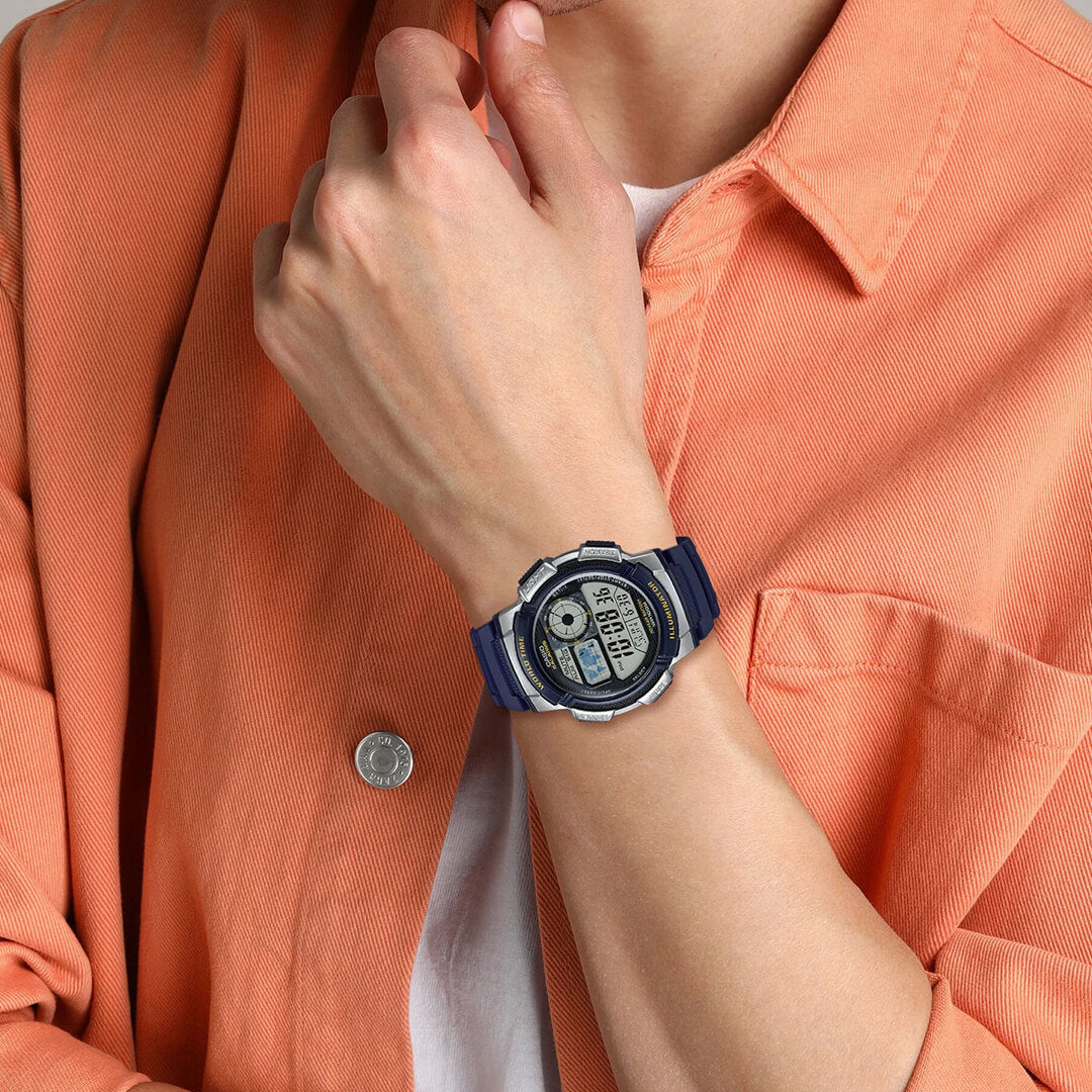 Casio AE-1000W-2AV azul puesto en la muñeca con camisa naranja