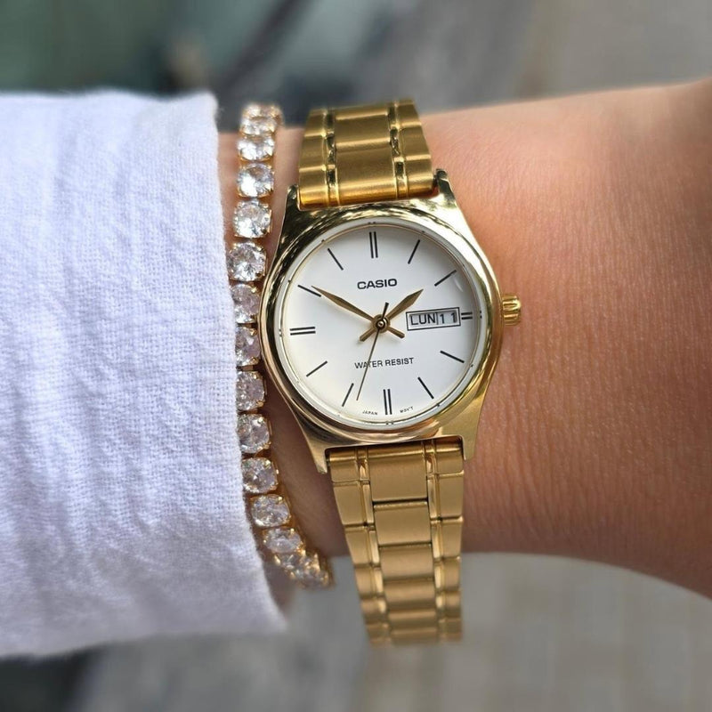Reloj Casio LTP-V006G-7B dorado con esfera blanca para mujer puesto en muñeca.