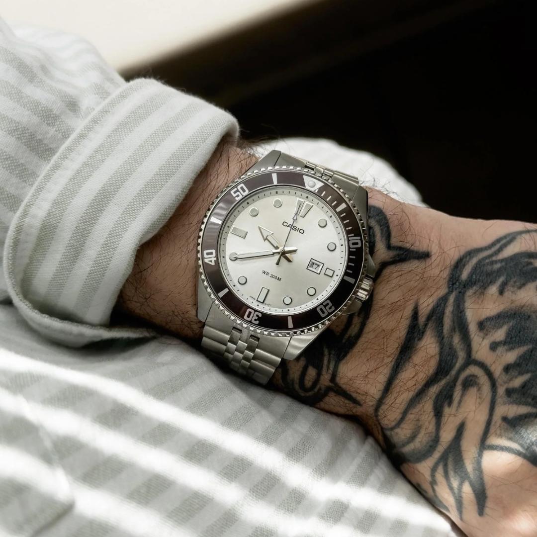 Vista lateral del Reloj Casio MDV-107D-7A con bisel giratorio plateado, con ropa casual.